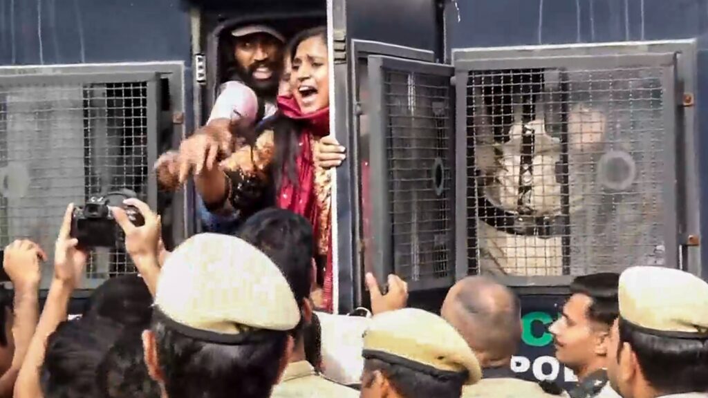 Protesters confront police officers behind metal barriers during a demonstration.