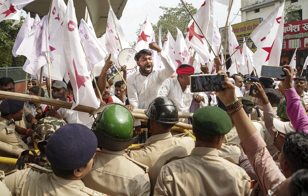 Protesters and police clash during Tiranga march in Delhi, with flags and crowd in focus.