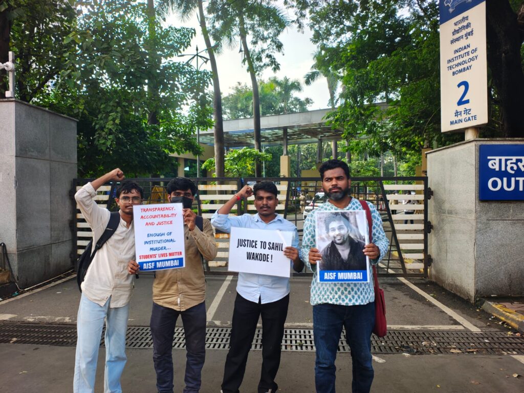 Protesters outside IIT Bombay demanding justice for Sahil Wakode, holding signs and photos.