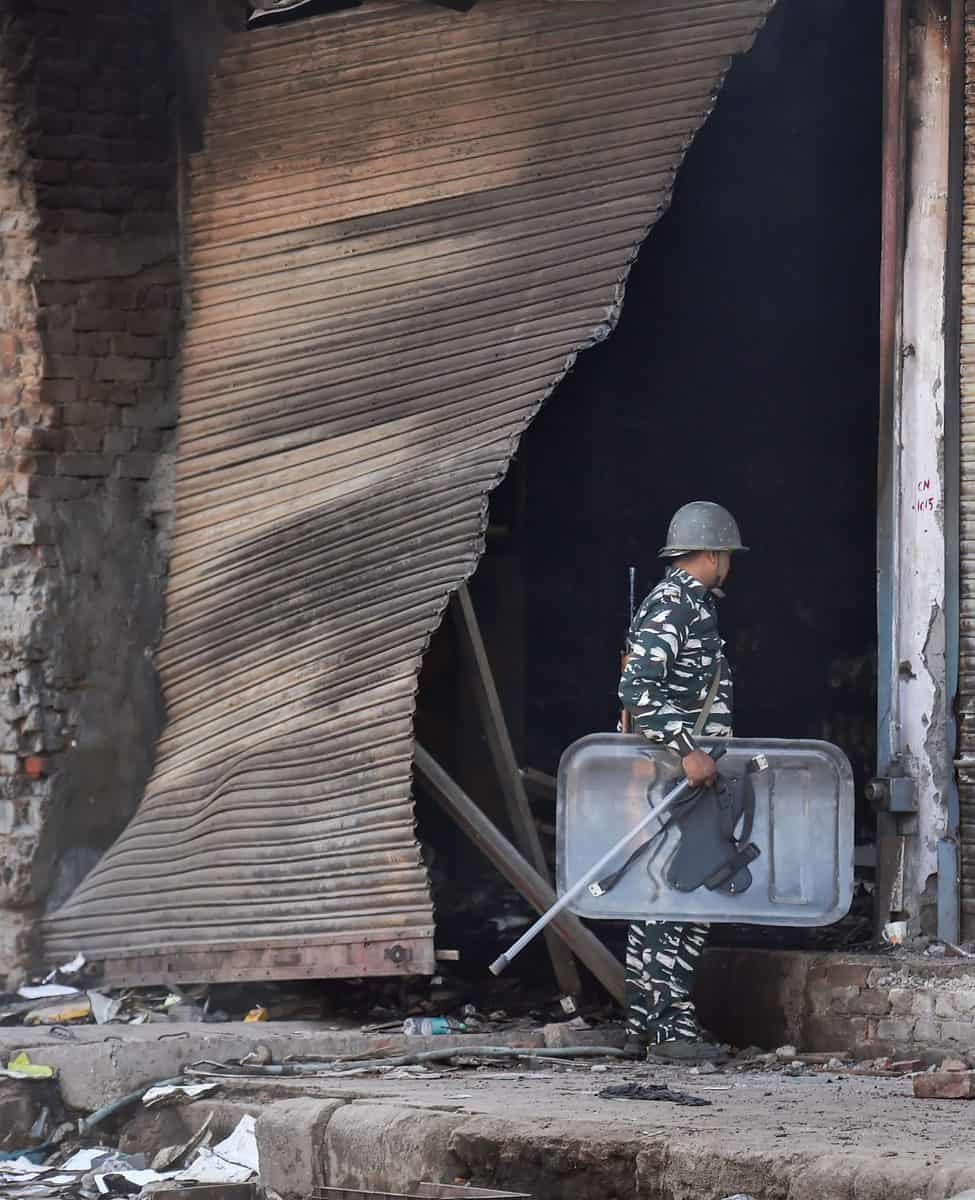 A security personnel inspects a damaged property in Bhagirathi Vihar area of the riot-affected northeast Delhi
