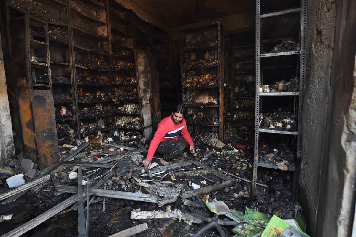  A shopkeeper sorts through the charred remains of a vandalized and burned shop, following Tuesday's violence, at Khajuri Khas extension area of northeast Delhi
