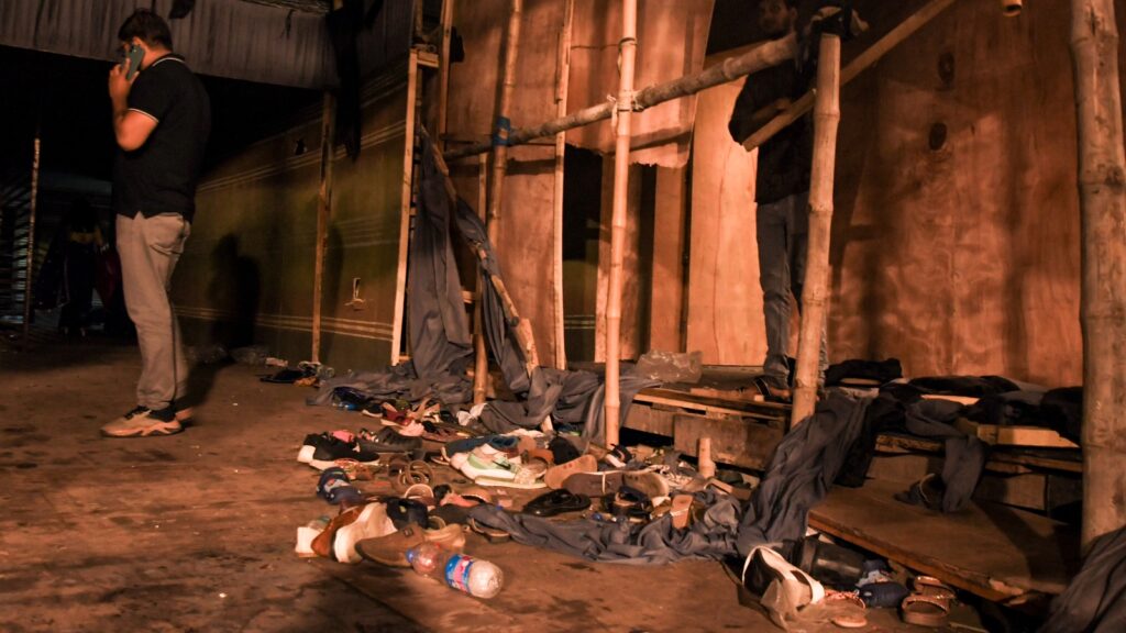 Clothes and shoes scattered on the ground in a dark, narrow lane after a stampede in Kolkata.