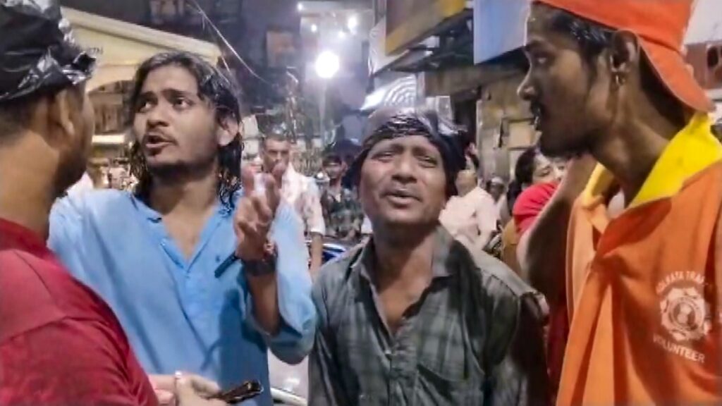 Group of people in a crowded street, some arguing, during a Kolkata stampede incident.