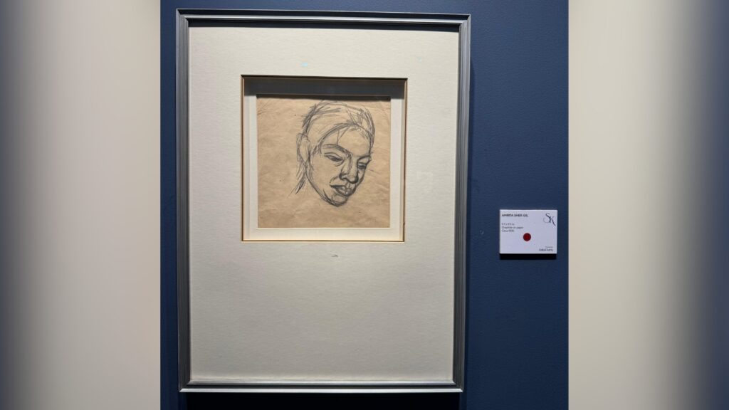 Sketch of a woman's face in a simple black frame at an art exhibition.