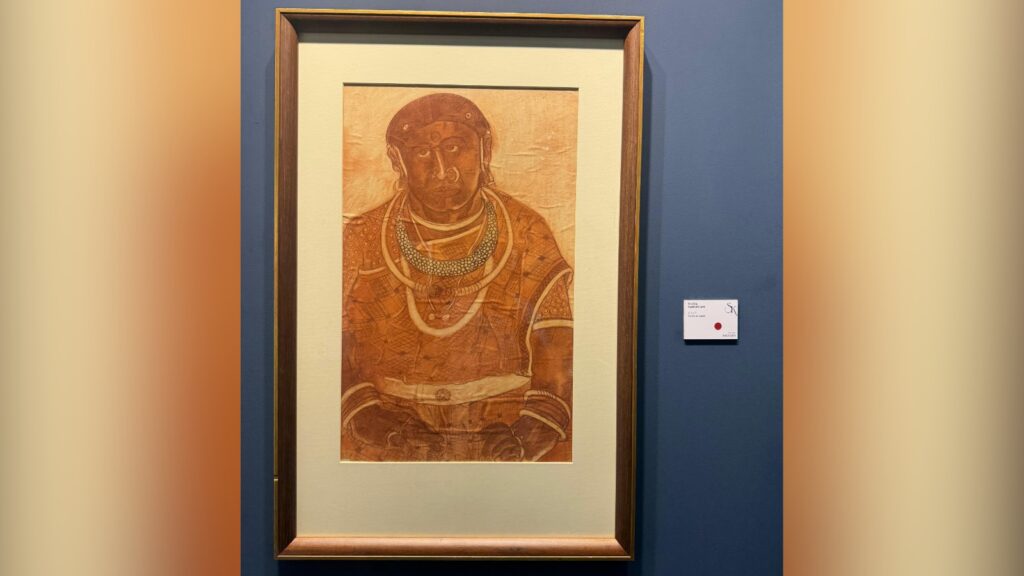 Ancient Indian painting of a woman with traditional jewelry and attire displayed in a frame.