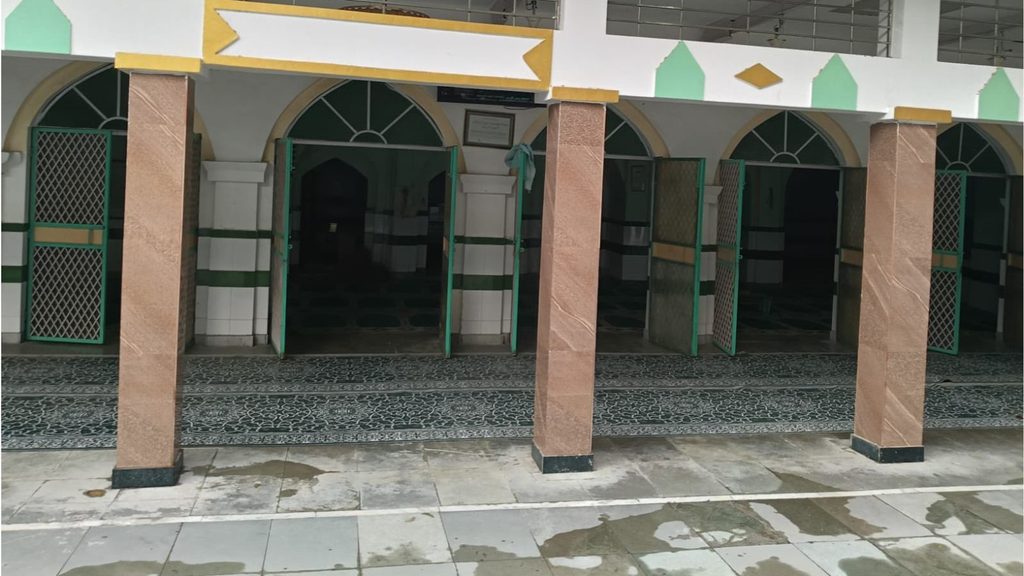 Empty mosque entrance with green and beige arches in Delhi, India.