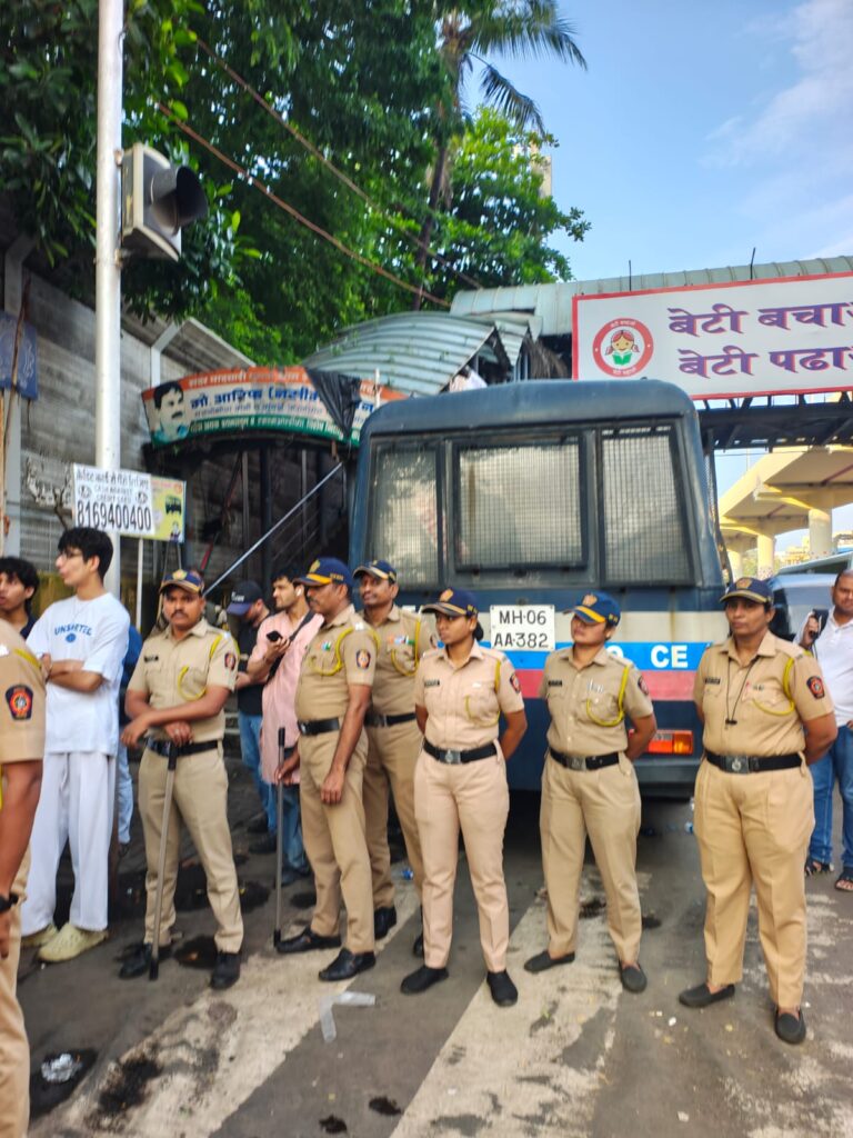 Police officers standing in front of a police vehicle during a public event in India.