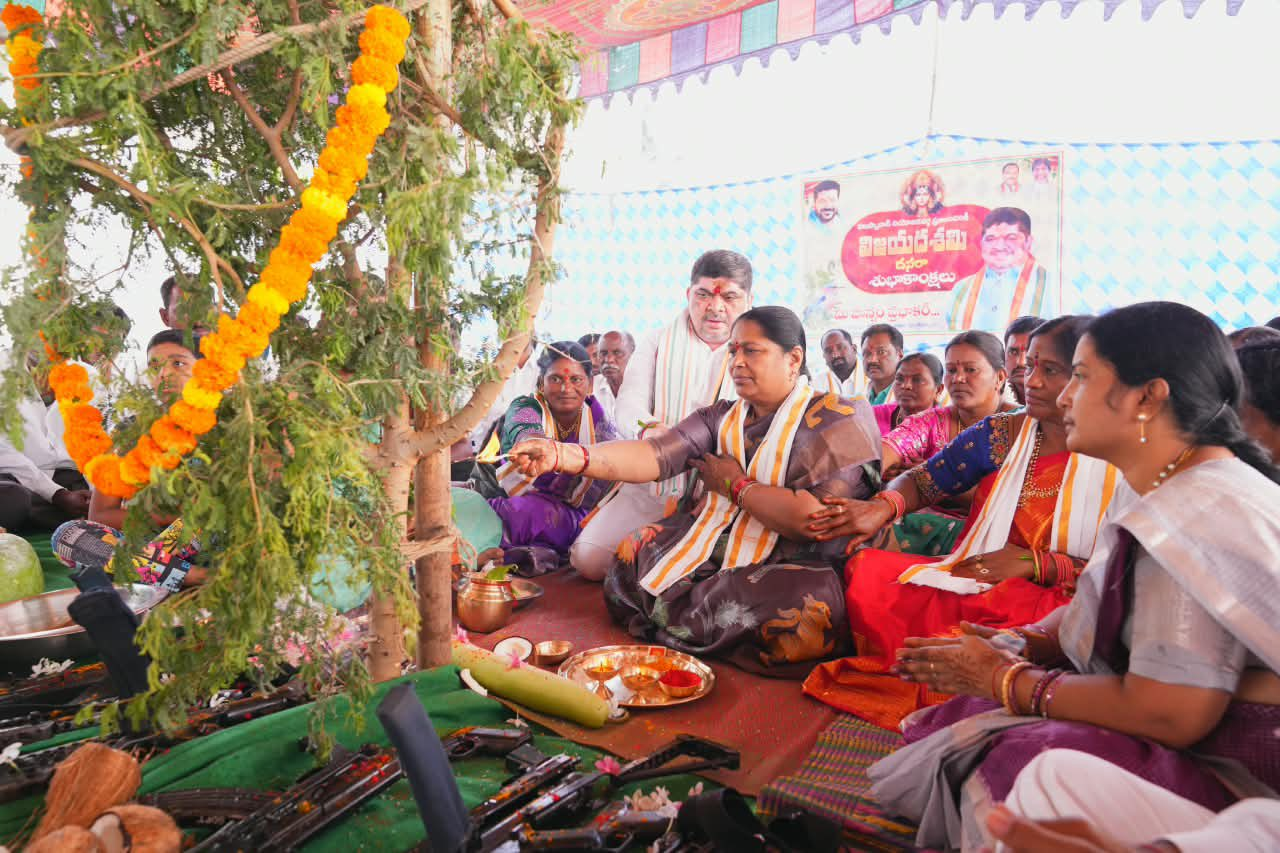 Women performing a traditional ritual under a decorated tree during a festival in India.